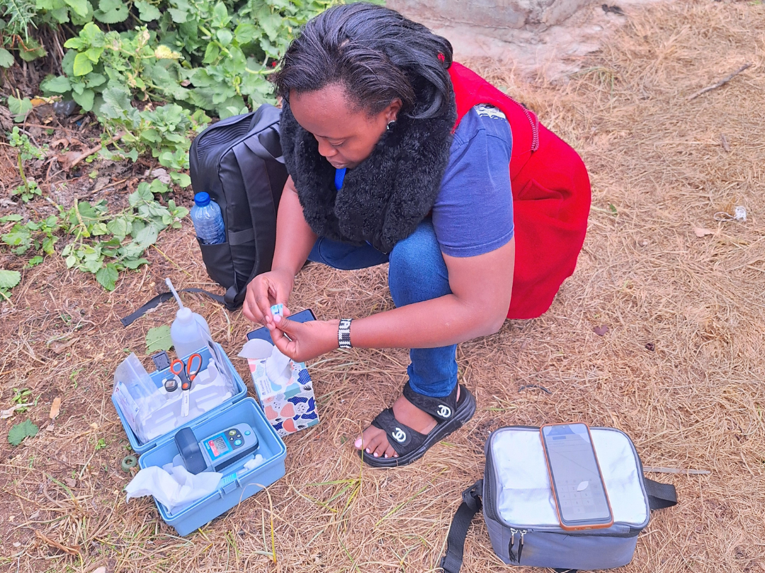 A lady kneels to measure chlorine levels from a water sample.