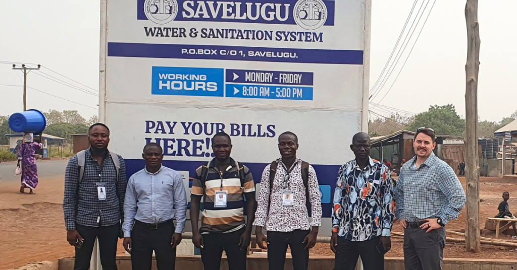 A group photo of Aquaya team members gathered together, smiling at the camera. The image represents the team working on water research and development projects, including studies on Piped Water Suppliers Performance in Ghana.