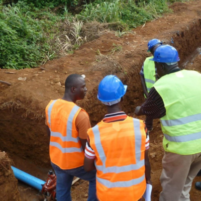 Sanitation workers standing in front of a water pipe.