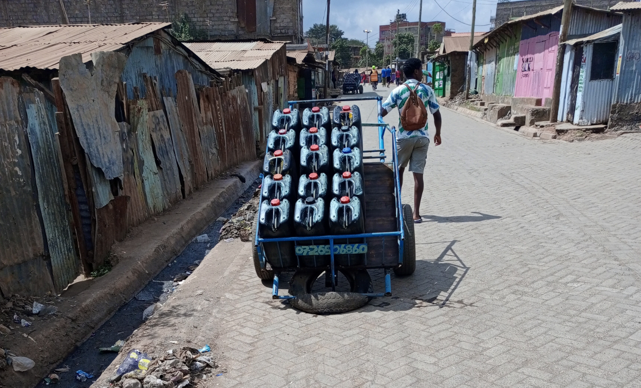 Water provider walking down the street pulling a hand-drawn cart.