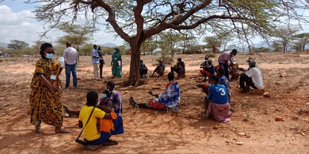 A group of community members sitting and standing in a circle.